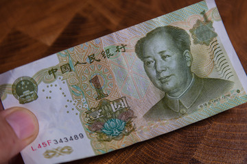 Fototapeta premium Male hand with a fan of 1 Renminbi or Chinese yuan or abbreviated RMB banknote, the official currency of the peoples republic of china. On front side the portrait of Mao Zedong, Paper Money of china