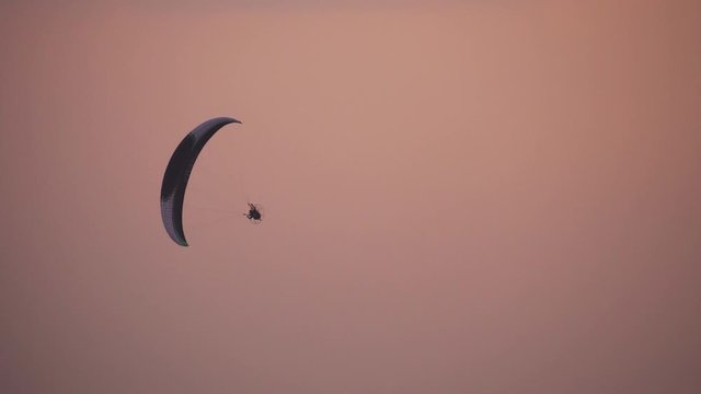 Paramotor gliding flying in the orange sky