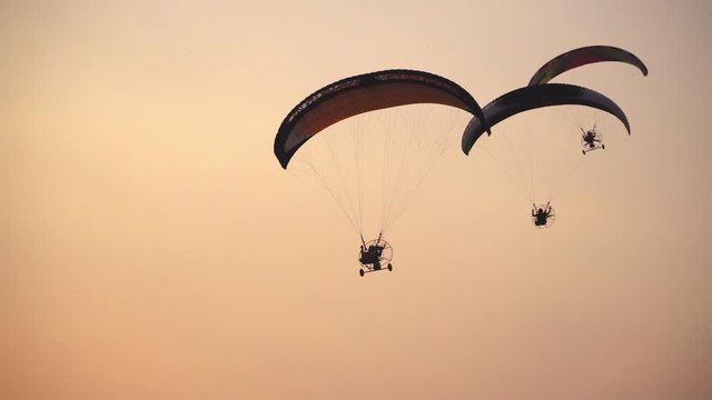 People who ride gliders, paramotor 3 planes in the sky beautifully.