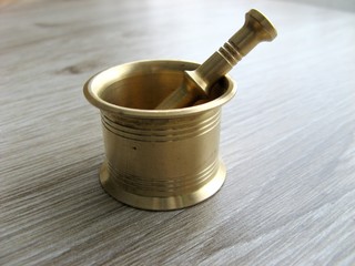 Close up of mini Brass Mortar and Pestle on wooden background.
