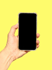 hand holding smart phone with blank screen isolated on yellow