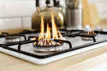 Macro closeup of modern luxury gas stove top with blue fire flame knobs bokeh blurry blurred...