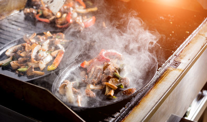 Chef cooking beef stew with carrots, onion and mushrooms in a wine sauce. Restaurant.