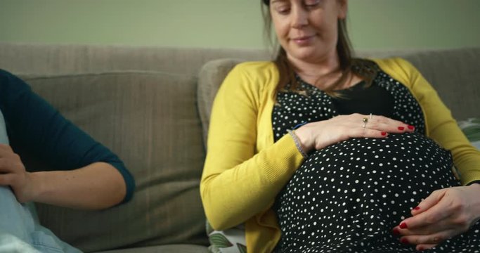Two pregnant women comparing their baby bumps