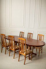 A classic set of wooden furniture for the kitchen. A set of chairs to the table in a classic interior