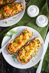 Baked stuffed eggplant with minced meat with cheese on a white plate on a wooden table, top view