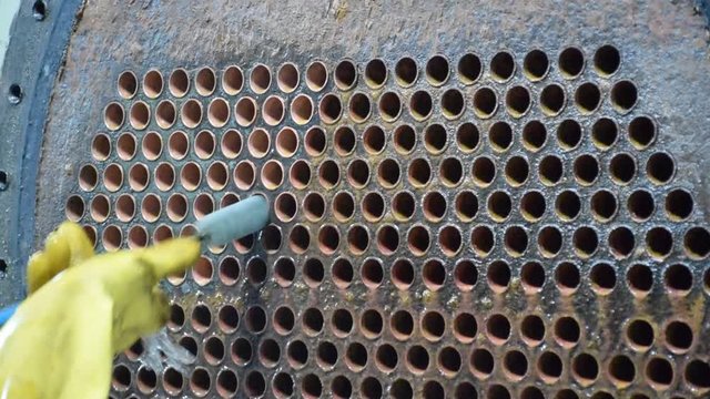 Mechanic is using brush to clean condenser tube of Chiller - HVAC System.