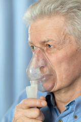 Portrait of sick senior man with inhaler
