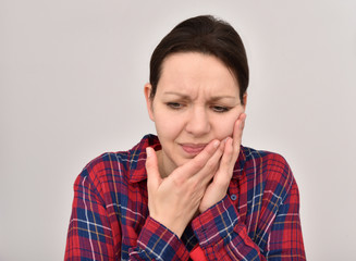 Woman with toothache and closed eyes holding her cheek. Isolated on the background.