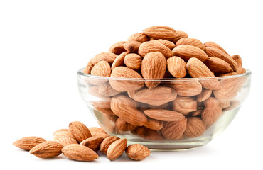 Almonds in a glass plate and scattered on a white. Isolated
