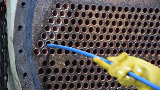 Mechanic is using brush to clean condenser tube of Chiller - HVAC System.