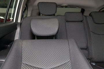 Upholstery of the seats of the passenger compartment with headrest of a luxury car with black fabric material in a workshop for hauling vehicles with a seam of thread.