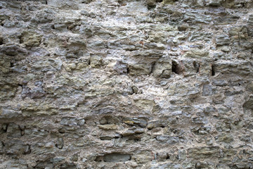 Old stone wall of a medieval castle. Grey colour. Rough old stone. Background.