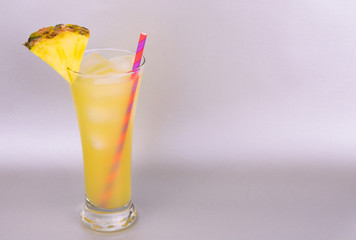 Pineapple juice in a tall glass isolated on a gray background. Copy space.