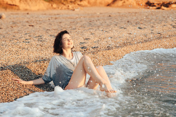 A young girl is sunbathing on a beach made of pebbles, taking sun and sea baths.