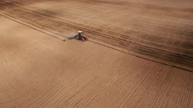 An aerial view of tractor planting potatoes in the fertile farm fields of Idaho, during the spring.