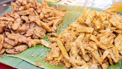 Banana chips and fried potatoes are placed on the banana leaf that is sold at the shop.
