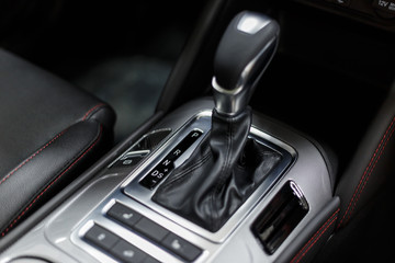 Fototapeta na wymiar Selector automatic transmission with leather in the interior of a modern expensive car. The background is blurred. Black leather car interior. Luxurious car instrument cluster. Close up shot