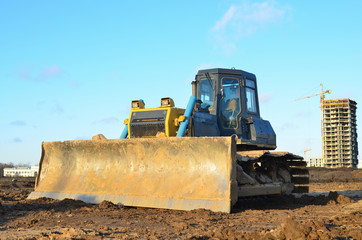 Bulldozer during land clearing and foundation digging at large construction site.  Crawler tractor with bucket for pool excavation and utility trenching. Dozer, Earth-moving equipment.