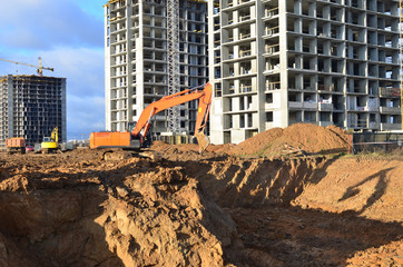 Excavator load the sand to the heavy dump truck on construction site. Excavators and dozers digs the ground for the foundation and construction of a new building. Apartment renovation program