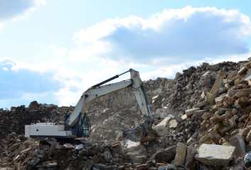 Salvaging and recycling building and construction materials. Industrial waste treatment plant. Excavator work at landfill with concrete demolition waste. Re-use concrete for new construction