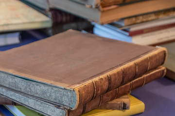 Shabby old books stacked in a pile on an old table with a fabric surface. Blurred background.