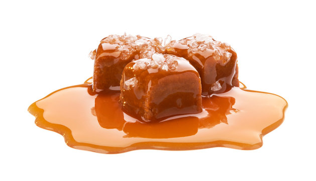 Salted toffee candies with caramel sauce isolated on white background
