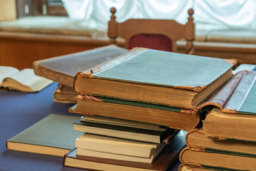 Shabby old books stacked in a pile on an old table with a fabric surface. Blurred background.