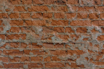 Brick wall with cement remains between bricks. Background image or screen saver. The bricks are brown. Uneven surface of old brickwork.
