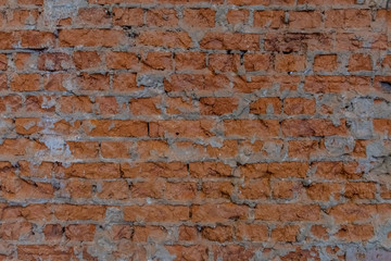Naklejka premium Brick wall with cement remains between bricks. Background image or screen saver. The bricks are brown. Uneven surface of old brickwork.