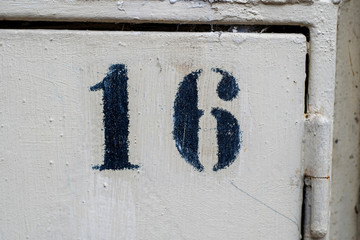 Close-up of part of a gray steel door with number 16 written