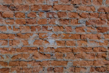 Brick wall with cement remains between bricks. Background image or screen saver. The bricks are brown. Uneven surface of old brickwork.