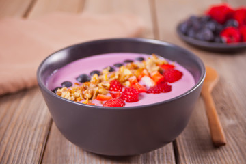 Smoothie bowl with berries on a wooden table.