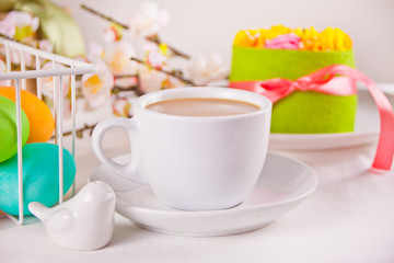 A cup of tea, small spring cake, flowers sakura, colorful eggs for Easter day. Spring concept.