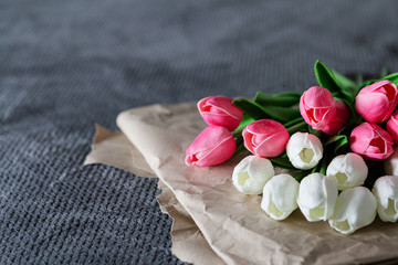 Fresh bouquet of white and pink tulips over recycled paper on gray background