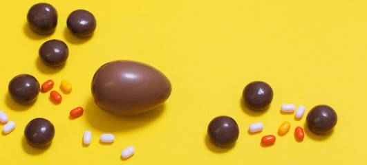 Easter yellow background with chocolatte eggs and  candy