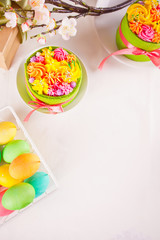 Spring Easter festive table. Two small green cake with butter cream flowers and colorful eggs on the background. Top view. Copy space.
