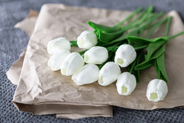Fresh bouquet of white tulips over recycled paper on gray background