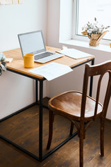 a reporter, journalist has left his laptop in the bedroom, close up side view photo.yellow cup, folder, paper, documents are on the table. working space