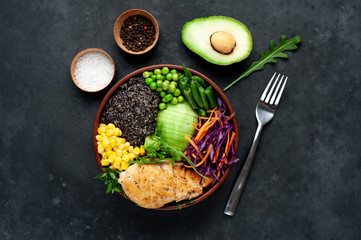 Bowl Buddha.Quinoa, chicken breast, avocado, red cabbage, arugula, carrot, green  peas, corn, broccoli, green beans in a plate on a stone background.
