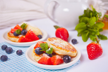 Cottage cheese pancakes, syrniki with berries and powdered sugar.