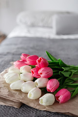 Fresh bouquet of white and pink tulips over recycled paper on gray background
