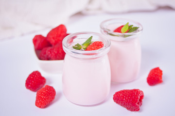 Two portions natural homemade yogurt in a glass jar with fresh raspberry. Breakfast concept.