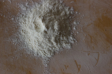 Scattered flour on wooden background. Scattered flour on the table. A bunch of flour scattered on the table