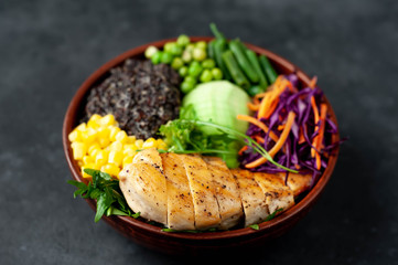 Bowl Buddha.Quinoa, chicken breast, avocado, red cabbage, arugula, carrot, green  peas, corn, broccoli, green beans in a plate on a stone background.