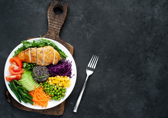 Bowl Buddha.Quinoa, chicken breast, arugula, avocado, red cabbage, carrot, green  peas, corn, tomato, green beans in a white plate on a stone background. with copy space for your text