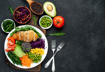 Bowl Buddha.Quinoa, chicken breast, arugula, avocado, red cabbage, carrot, green  peas, corn, tomato, green beans in a white plate on a stone background. with copy space for your text