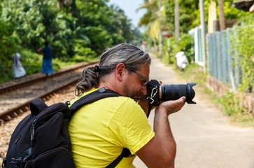 professional photographer of Caucasian traveler with long hair takes a picture in a tropical country, Asia Sri Lanka