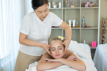 Beautiful caucasian woman sleeping rest relax on bed for spa asia massage at luxury spa and relaxation. Thai masseuse massaged her face and head in the spa room for office syndrome treatment