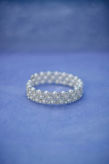 Jewelry for the bride: a bracelet with pearl beads on a blue-purple background. Selective focus